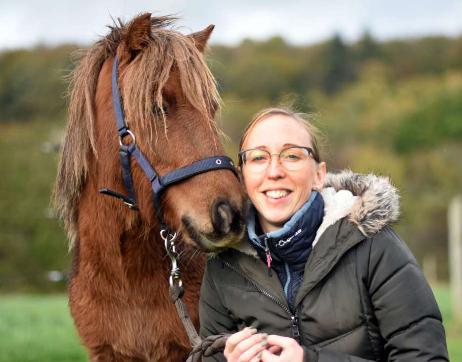 Amélie Focant souriante à côté d'un cheval brun